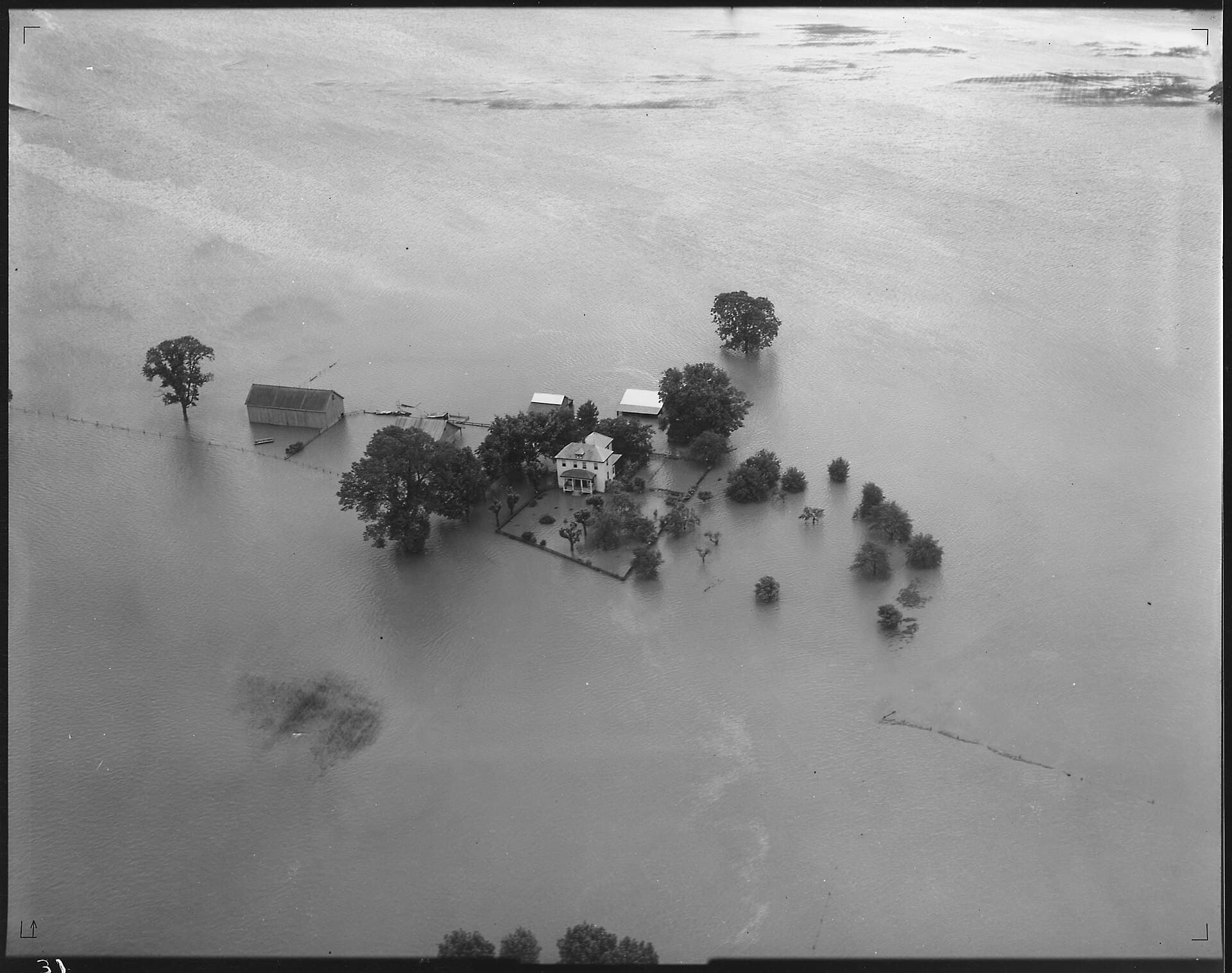 Aerial view of a farmstead surrounded by flood water - NARA - 285955
